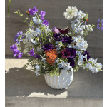 Mixed purple and white flowers arranged in a white vase