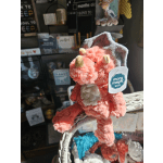 Plush pink dragon toy with a tag on a display basket