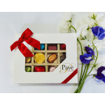 Box of assorted chocolates beside white and purple flowers