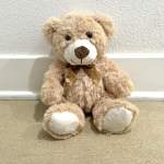 Plush teddy bear with a ribbon bow sitting on the floor