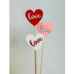 Three heart-shaped signs on sticks with the word love
