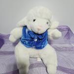 White plush lamb wearing a blue vest on purple mesh fabric