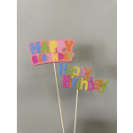 Colorful birthday cake toppers on sticks against a gray wall