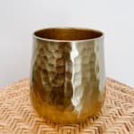 Hammered gold metal vase on a woven mat
