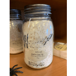 Glass jar of bath salts with a metal lid on a shelf