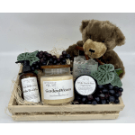 Gift basket with a teddy bear, candles, soap, lotion, scrub, and faux grapes