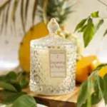 Decorative glass candle jar with a lid, surrounded by flowers and greenery