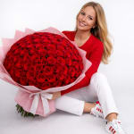 Woman holding a large bouquet of red roses wrapped in pink paper