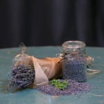 Bundle of dried lavender beside a glass jar filled with lavender buds