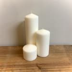 Three white pillar candles on a wooden surface