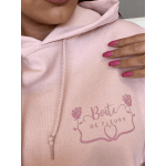 Person wearing a light pink hoodie with rose graphic text