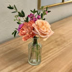 Small bouquet of peach and pink flowers in a clear glass vase