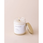 Lit candle in a glass jar with a gold lid beside it