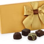 Gold gift box with a satin bow and assorted chocolates