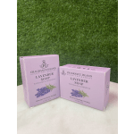 Two lavender soap boxes on a white surface against a green backdrop