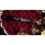 Red rose bouquet with a black ribbon reading "Por Bonita" and gold butterfly accents