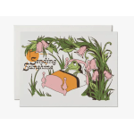 Greeting card with a frog in bed surrounded by pink flowers