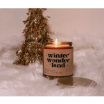 Lit candle in a glass jar with a gold lid beside a glittery tree decoration