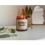 Lit amber candle in a glass jar beside a small potted plant