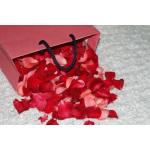 Red gift bag spilling rose petals onto a light carpet