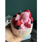 Small pink cake topped with a teddy bear and berries