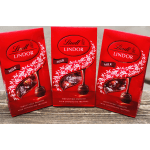 Three red Lindt Lindor milk chocolate truffle boxes on a wooden surface