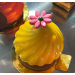 Yellow glazed dessert topped with a pink flower decoration