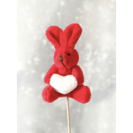 Small red plush bunny on a stick holding a white heart against a soft gray background