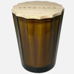 Amber glass candle jar with a wooden lid labeled Sand + Fog