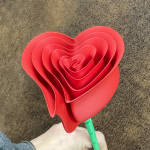 Red heart-shaped layered paper flower on a green stem