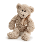 Plush teddy bear with a satin bow sitting on a small base