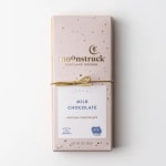 Milk chocolate bar in a pale pink wrapper with gold speckles and a gold string bow