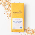 Yellow milk chocolate salted toffee bar with scattered toffee pieces on a white surface
