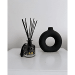 Black reed diffuser bottle with a round black vase beside it