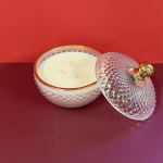 Decorative glass candle jar with a lid on a red background