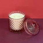 Glass candle jar with a lid on a red surface
