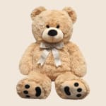 Plush teddy bear with a satin bow on a plain background