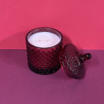 Red glass candle jar with a lid on a pink background