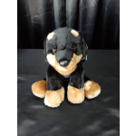 Plush black-and-tan dog toy sitting on a dark surface