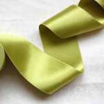 Lime green satin ribbon curled on a white surface