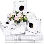 Pink and white rose bouquet in a small white vase, surrounded by white boxes