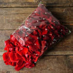 Bundle of red rose petals in clear plastic wrap on a wooden surface