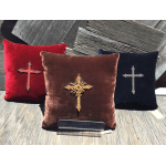 Three velvet pillows with jeweled cross designs on a wooden surface.