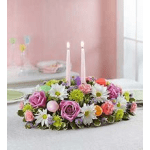 Low floral centerpiece with pink roses and white daisies around two taper candles