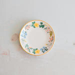 Round floral-patterned plate with yellow rim on a light surface