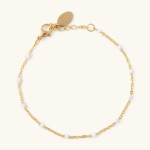 Gold chain bracelet with small white beads on a light background