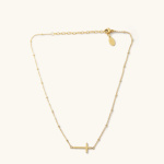 Gold necklace with a small cross pendant on a light background