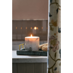 Lit white pillar candle in a green tray with a woven accent