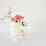 White cake topped with pink and white flowers and macarons