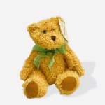 Golden teddy bear with a green ribbon bow